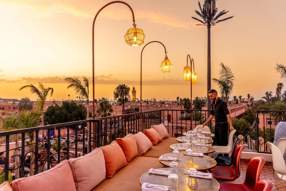 Waiter preparing tables on the Coco Rooftop terrace at sunset